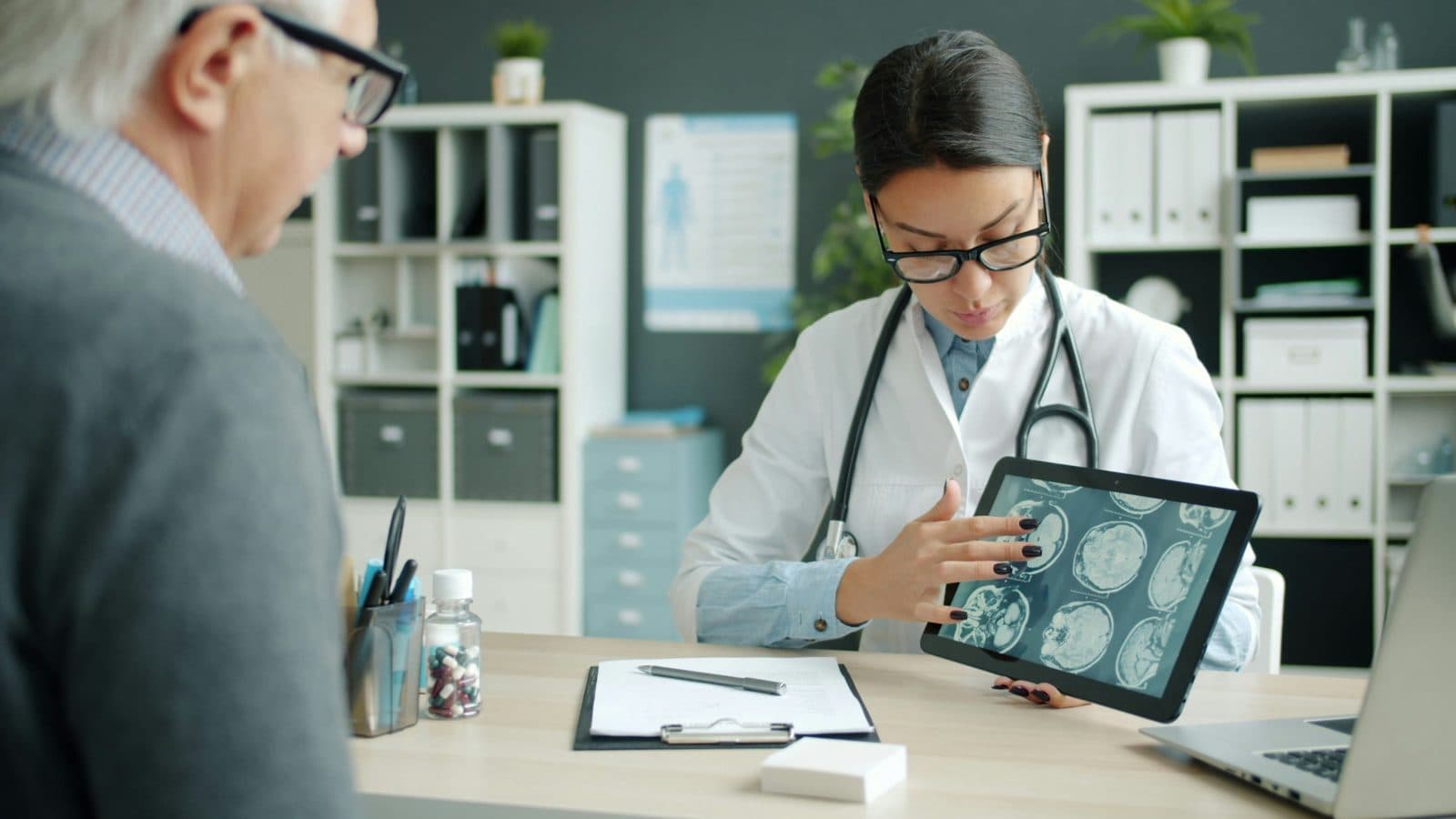 Doctor explaining brain scan results on a tablet to an older patient