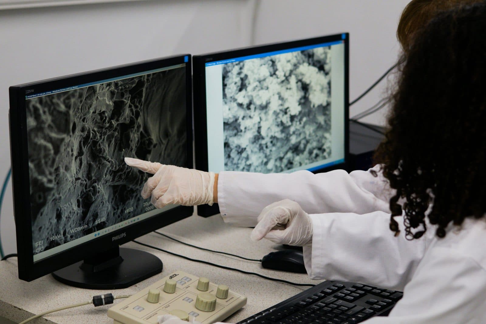 Engineer in a lab coat reviewing device imaging output on two monitors