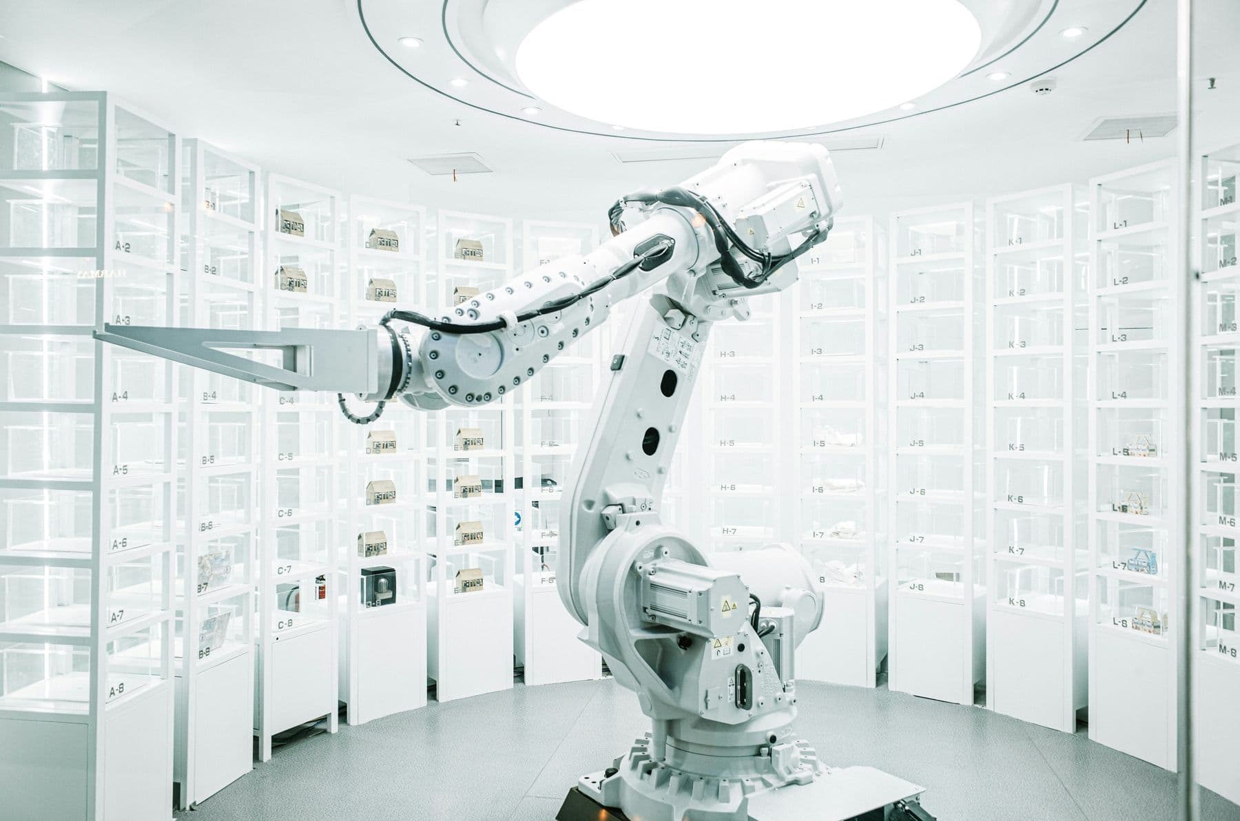 White industrial robot arm in a clean, brightly lit automated storage hall