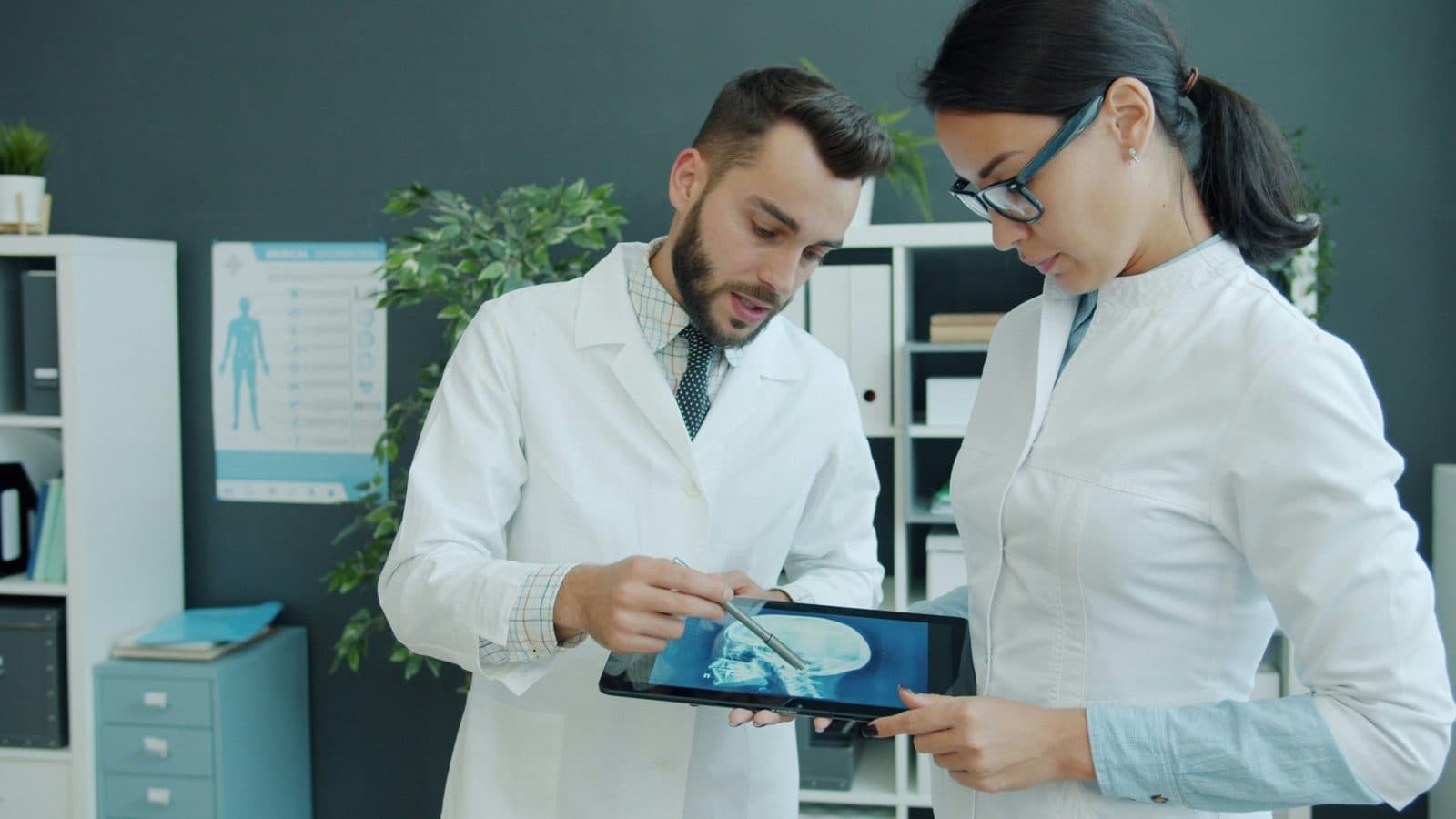 Two clinicians reviewing a skull X-ray on a tablet